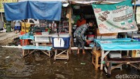 Para pedagang tetap menggelar lapak meski banjir rob menerjang kawasan tersebut.