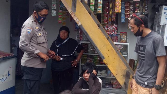Rusli (19) (tengah) ditangkap polisi usai melempari ibunya dengan batu (Hermawan-detikcom).