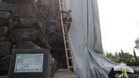 Petugas bersiap menggunakan pakaian standar keselamatan untuk naik bangunan Candi Mendut saat proses penutupan menggunakan terpaulin.  