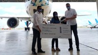 Direktur Utama Garuda Indonesia Irfan Setiaputra (kanan) menyerahkan cinderamata kepada Johana Angelia Christian (tengah) selaku pemenang tahap keempat kompetisi “Fly Your Design Through the Sky, disaksikan Direktur Layanan, Pengembangan Usaha & Teknologi Informasi Garuda Indonesia, Ade Susardi (kiri) usai penyerahan hadiah, di Hanggar Garuda Indonesia, Cengkareng, Senin (30/11/2020). 