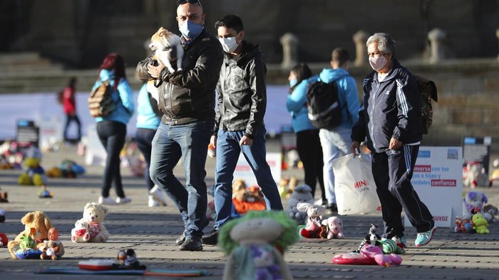 Ratusan Mainan Jadi Simbol Aksi Kekerasan Pada Anak People walk past toys representing victims of child violence, that were placed during a protest at Bolivar square in Bogota, Colombia, Monday, Nov. 30, 2020. Hundreds of stuffed animals, dolls and action figures were laid out in Bogota's iconic Bolivar Square to protest violence against children and demand more funding for organizations that help children who have been growing up without their parents. (AP Photo/Fernando Vergara)