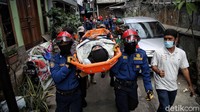 Petugas damkar memperagakan mengevakuasi warga korban banjir yang sedang sakit.