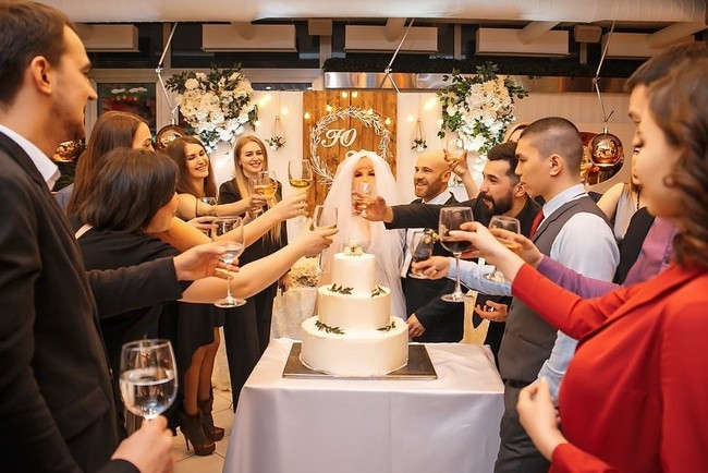 Pesta pernikahan berlangsung meriah dengan sesi bersulang bersama. Terdapat pula kue pernikahan untuk disantap bersama. (Foto: Instagram/@yurii_tolochko)