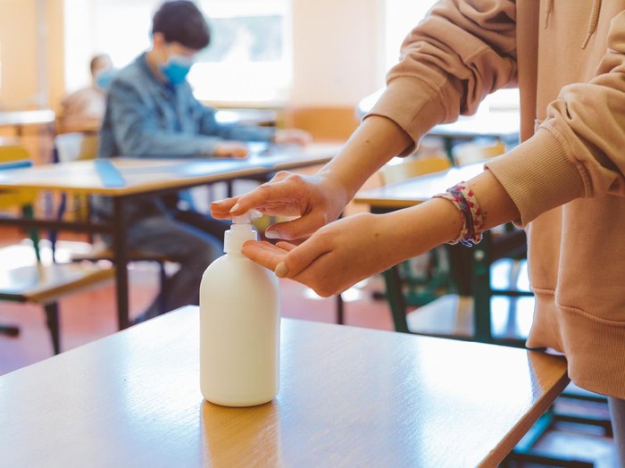 School students  using hand sanitizer after entering a classroom.