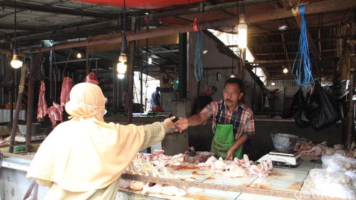 Seorang pedagang daging ayam di pasar Bandung tengah melayani pembeli.