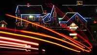 Lalu lintas pagi meninggalkan seberkas cahaya saat melewati toko barang antik dan souvenir yang dihiasi lampu di Naples, Maine. AP Photo/Robert F. Bukaty  