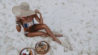 Ia juga tak lupa bermain di pantai. Ia mengabadikannya sambil berpose dengan makanan. Ada irisan buah segar dan nachos. Foto: Instagram @alexissharkey
