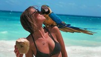 Saat bermain di pinggir pantai, tentu saja Alexis tak melewatkan minum kelapa muda yang segar. Ia juga berpose dengan burung kakak tua. Foto: Instagram @alexissharkey