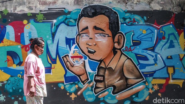 Muncul Grafiti DKI-1 Tumbang di Cikini Warga melintas di depan grafiti 'Tumbang' di kawasan Cikini, Jakpus. Tulisan 'Tumbang' dilengkapi mural karakter pria mengenakan baju coklat dengan nametag 'DKI-1'.