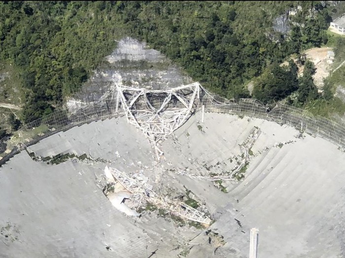 This photo provided by Aeromed shows the collapsed Radio Telescope in Arecibo, Puerto Rico, Tuesday, Dec. 1, 2020. The already damaged radio telescope that has played a key role in astronomical discoveries for more than half a century completely collapsed, falling onto the northern portion of the vast reflector dish more than 400 feet below. (Yamil Rodriguez/Aeromed via AP)