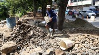 Pekerja mengangkut batu untuk pengerjaan turap Kali Baru.