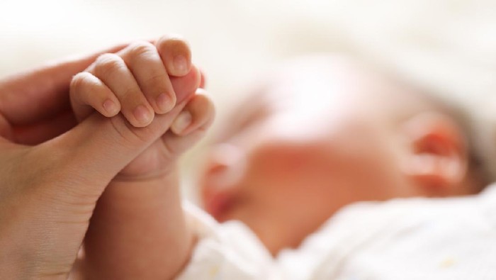 Sleeping baby clenches his parents fingers; Soft focus and blurry
