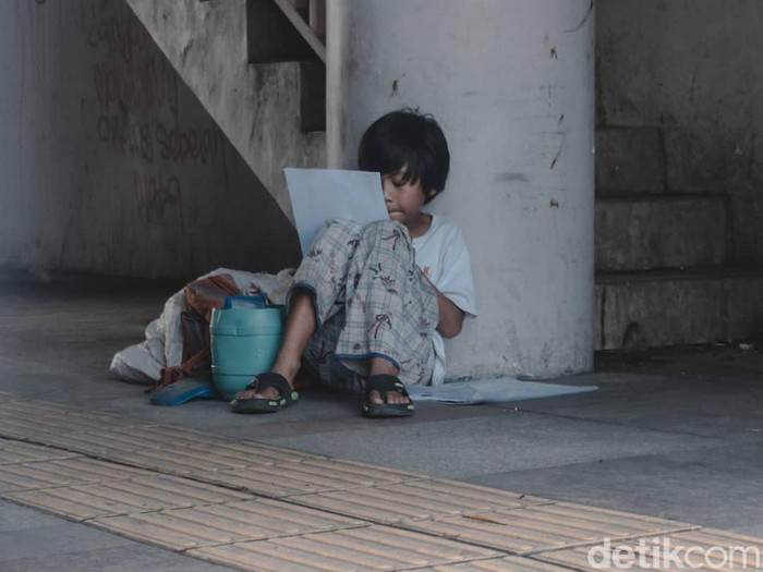 Bocah pemulung mengerjakan tugas di trotoar Kota Bandung