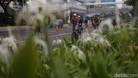 Pesepeda diarahkan untuk gowes di lajur sebelah kiri yang telah ditandai barier oranye. Sementara itu, pengendara motor dan mobil melintas di lajur kanan.