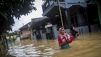 Warga berjalan melintasi banjir di Desa Wantisari, Lebak, Banten, Minggu (6/12/2020). 