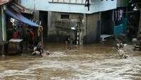 Anak-anak di bantaran Ciliwung menjadikan genangan banjir untuk mandi.