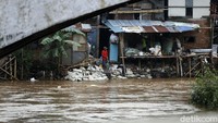 Seorang warga memanfaatkan banjir untuk mencari barang bekas yang hanyut. Barang bekas yang dikumpulkan sepert botol bekas.
