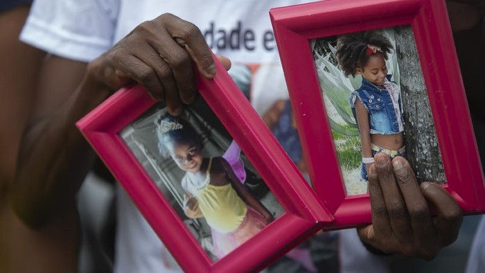 Ana Lucia Silva Moreira, 38, mother of Emily Victoria Silva dos Santos, 4, and aunt of Rebeca Beatriz Rodrigues dos Santos, 7, holds photos of the two girls during a protest in Duque de Caxias, Rio de Janeiro state, Brazil, Sunday, Dec. 6, 2020. Emily Victoria Silva dos Santos and Rebeca Beatriz Rodrigues dos Santos, were killed by stray bullets while playing outside their homes. (AP Photo/Bruna Prado)