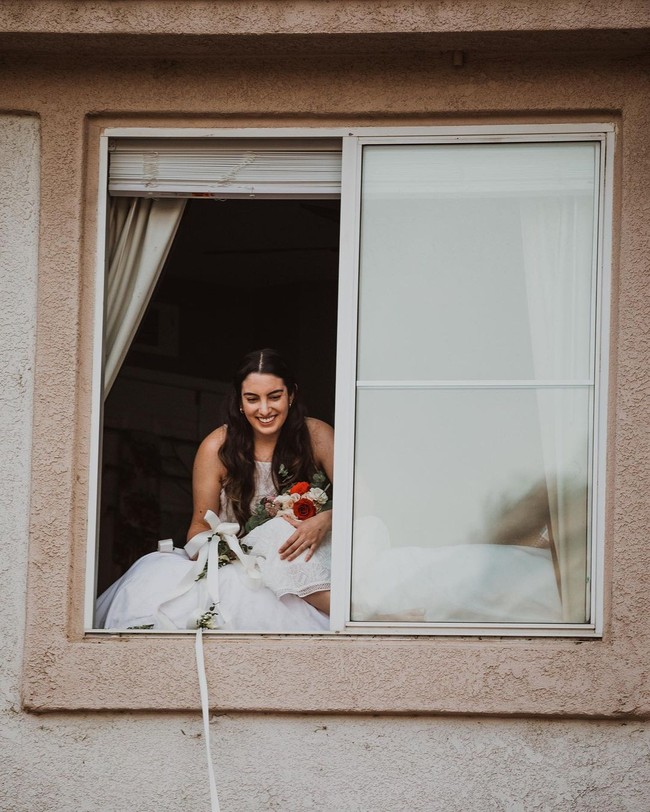 Beginilah suasana unik pernikahan pasangan asal California, AS bernama Lauren dan Patrick Delgado. Ya, pengantin wanita, Lauren yang positif Corona sebelum hari H menyaksikan pernikahan dari atas jendela rumahnya.  Foto: dok. Fotografer: Jessica Jackson/Instagram @jesscaste