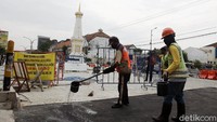 Dua orang pekerja sedang melakukan pengaspalan.