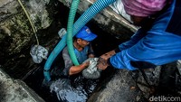 Sejumlah petugas berjibaku mengangkat sampah dan kotoran dari selokan di kawasan Gambir, Jakarta.