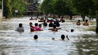 Sejumlah warga mengarungi banjir yang merendam  ibukota Lhoksukon, Aceh Utara, Aceh, Senin (7/12/2020).