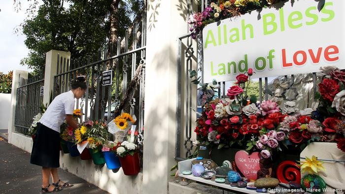 Seorang perempuan meletakan bunga di depan pintu masuk Masjid An-Nur di Christchurch, Selandia Baru.