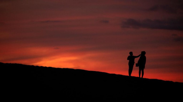 Vegetasi Bukit Pasir di Spanyol Kembali Pulih Akibat Pandemi MASPALOMAS, SPAIN - DECEMBER 05: People enjoy the sand dunes at sunset on December 05, 2020 in Maspalomas, Spain. The dunes at Maspalomas have seen a positive transformation during the Coronavirus pandemic due to the lack of tourism on the Island. Conservation efforts over several years to restore the natural habitat have had a boost due to the lack of disturbance, as many of the dunes have regained their shape and height, and vegetation has started to recover. The area which is a site of special scientific interest and a nature reserve is, according to scientists, losing sand at a rate of 45,000 cubic metres per year, and has seen dunes shrinking by several metres over the last 60 years. (Photo by Dan Kitwood/Getty Images)