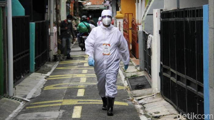 Petugas yang mengenakan APD dibersikan dengan cairan disinfektan oleh rekannya seusai berkeliling ke rumah warga yang mengalami isolasi, sakit dan juga lansia dalam penyelenggaraan Pilkada Kota Depok, Jawa Barat