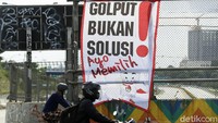 Pengendara sepada motor melintas di depan spanduk ajakan untuk tidak golpul di Pilkada serentak.