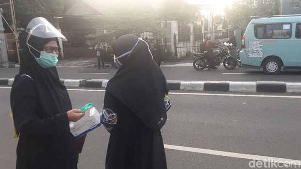 Sejumlah ibu-ibu membagikan bunga dan masker di depan Jl Petamburan III pada Rabu (9/12) sore (Afzal Nur Iman/detikcom)