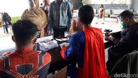 Superman bertugas memberikan surat suara kepada peserta.