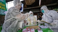 Petugas KPPS yang memakai pakaian APD lengkap siap melayani warga yang akan memberikan hak suaranya.
