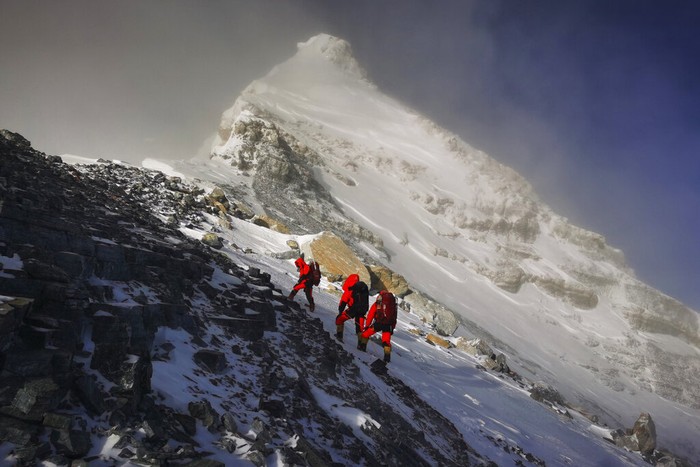 Foto ini dirilis Xinhua News Agency pada bulan Mei 2020: salah satu anggota tim survei China memasang peralatan di Gunung Everest yang oleh warga lokal dinamai Gunung  Qomolangma. China dan Nepal mengumumkan ketinggian baru Gunung Everest pada 8 Desember  2020 (Tashi Tsering/Xinhua via AP, File)