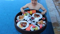 Floating breakfast jadi salah satu caranya menikmati liburannya. Menu sarapan yang dipilihnya lengkap, mulai dari sosis, roti, kopi sampai jus buah. Foto: Instagram @sahrulgunawanofficial