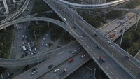 Suasana di jalan-jalan Kota Wuhan yang sepi dari kendaraan pada 3 Februari 2020 silam. Pemandangan itu tampak berbeda dengan foto di bawahnya yang dipotret pada tanggal 4 Desember 2020, dimana sejumlah kendaraan tampak hilir mudik di jalan tersebut. Getty Images/Getty Images.