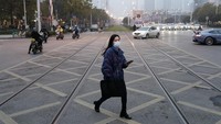 Seorang pejalan kaki tampak melintas di salah satu sudut Kota Wuhan yang sepi pada bulan Februari 2020 lalu. Kini kawasan itu tampak kembali sibuk dengan aktivitas warga dan kendaraan yang lalu lalang saat dipotret pada bulan Desember 2020. Getty Images/Getty Images.