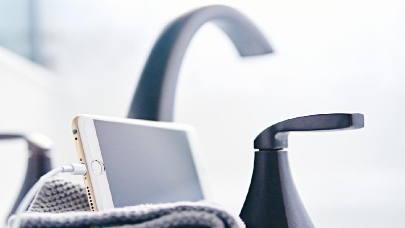 Peyton, Colorado, USA  - March 22, 2018: An iPhone 6s Plus plugged in to a charging cable rests on a clean washcloth next to the faucet on the side of a bathtub.