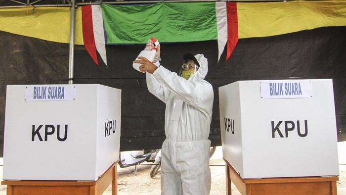 Petugas KPPS berpakaian baju hazmat dan alat pelindung diri (APD) menyemprotkan cairan disinfektan di Tempat Pemungutan Suara (TPS) 13, Cipayung, Depok, Jawa Barat, Rabu (9/12/2020). TPS di Kota Depok menerapkan protokol kesehatan pada Pilkada Serentak 2020 di masa Pandemi COVID-19. ANTARA FOTO/Asprilla Dwi Adha/wsj.