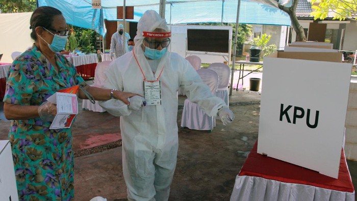 Petugas Kelompok Penyelenggara Pemungutan Suara (KPPS) berpakaian hazmat membantu pemilih menggunakan hak pilihnya di TPS 46 Paku Jaya, Serpong Utara, Tangerang Selatan, Banten, Rabu (9/12/2020). Penggunaan alat pelindung diri (APD) lengkap tersebut untuk meyakinkan masyarakat menggunakan hak pilihnya pada Pilkada Tangerang Selatan 2020 meski di tengah pandemi COVID-19. ANTARA FOTO/Muhammad Iqbal/wsj.