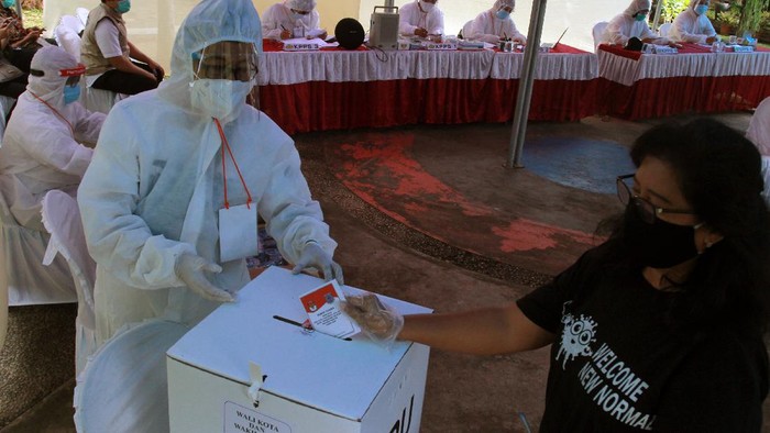 Petugas Kelompok Penyelenggara Pemungutan Suara (KPPS) berpakaian hazmat membantu pemilih menggunakan hak pilihnya di TPS 46 Paku Jaya, Serpong Utara, Tangerang Selatan, Banten, Rabu (9/12/2020). Penggunaan alat pelindung diri (APD) lengkap tersebut untuk meyakinkan masyarakat menggunakan hak pilihnya pada Pilkada Tangerang Selatan 2020 meski di tengah pandemi COVID-19. ANTARA FOTO/Muhammad Iqbal/wsj.