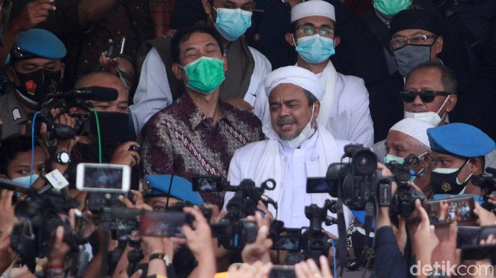 Habib Rizieq Shihab tiba di Polda Metro Jaya sebagai tersangka kasus kerumunan di Petamburan. Setiba di Polda Metro Jaya, ia sempat mengacungkan jempol.