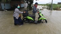 Warga mendorong motor yang mogok saat menerobos banjir.