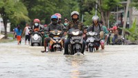 Warga mengendarai motor melintasi banjir di Jalan Benjeng, Kabupaten Gresik, Jawa Timur, Senin (14/12/2020).