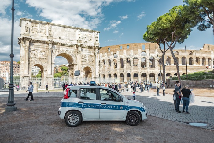 Rome, Italy - October 3, 2019: a police car in front of the Arch of Constantine near the Colosseum or Coliseum.
