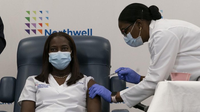 Sandra Lindsay (L), a nurse at Long Island Jewish Medical Center, is inoculated with the Covid-19 vaccine by Dr. Michelle Chester, at Long Island Jewish Medical Center, on December 14, 2020 in the Queens borough of New York. - The rollout of the Pfizer and BioNTech vaccine, the first to be approved by the Food and Drug Administration, ushers in the biggest vaccination effort in US history. More than 299,000 Americans have been killed by the virus, including over 35,000 residents of New York state. (Photo by Mark Lennihan / POOL / AFP)