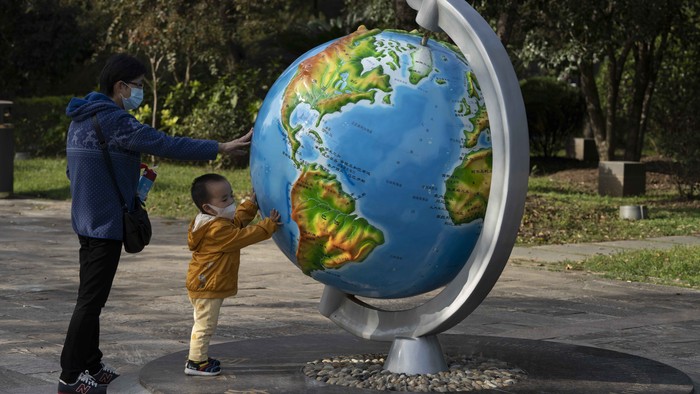 A child and woman, wearing masks to protect from the coronavirus, look at a giant globe in Wuhan on Thursday, Oct. 22, 2020. (AP Photo/Ng Han Guan)