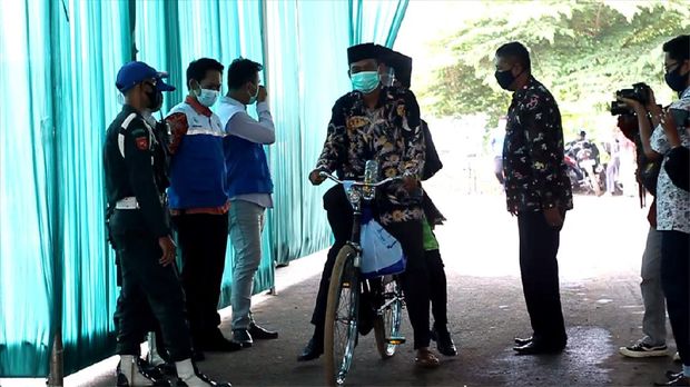 Bapak antar anak wisuda drive thru naik sepeda ontel di Institut Agama Islam Negeri (IAIN) Pekalongan, Jawa Tengah, Selasa (15/12/2020).