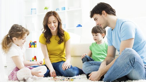 Cheerful siblings playing twister game on floor having fun at home on weekend. Kids friendship and leisure activities.