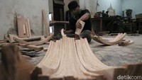 Seorang pekerja sedang melakukan proses pengeleman kayu yang akan dibuat menjadi kursi.
